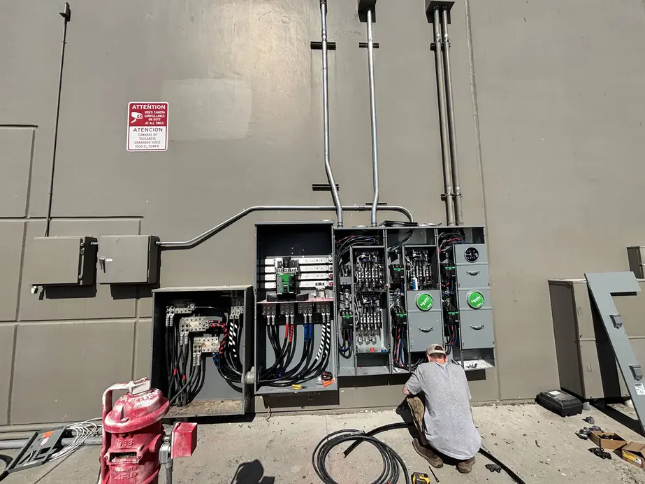 Thunder Electric's commercial meter bank work on a grey wall, new conduit runs above the cabinets